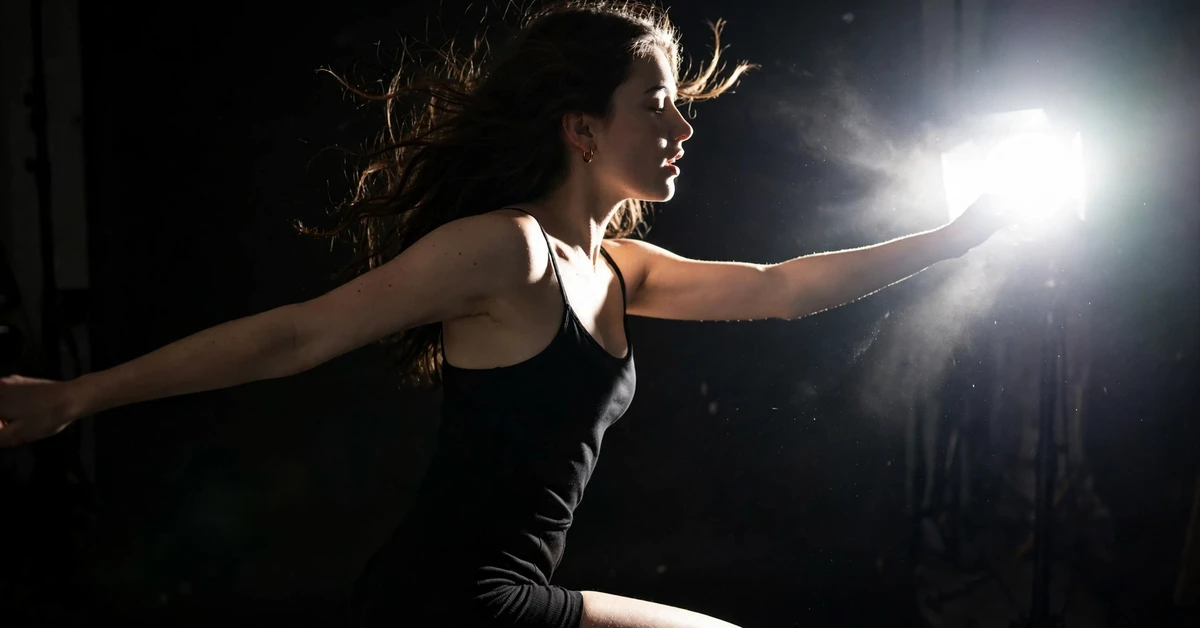 A model posing in a dark studio lit by a bright white flash burst.